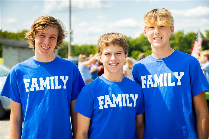 Three boys wearing family shirts smile